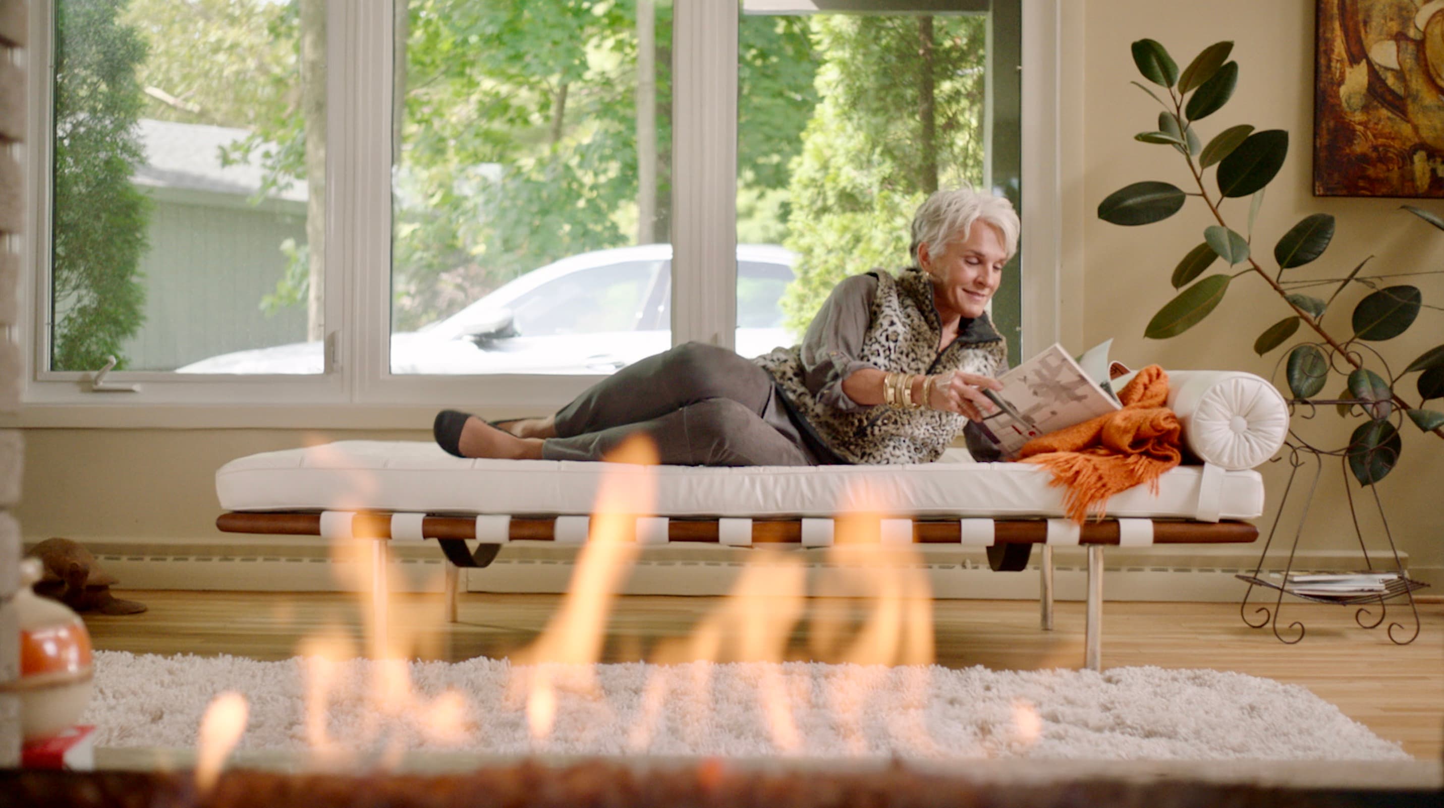 Screenshot of woman laying down reading with a fire roaring in the foreground